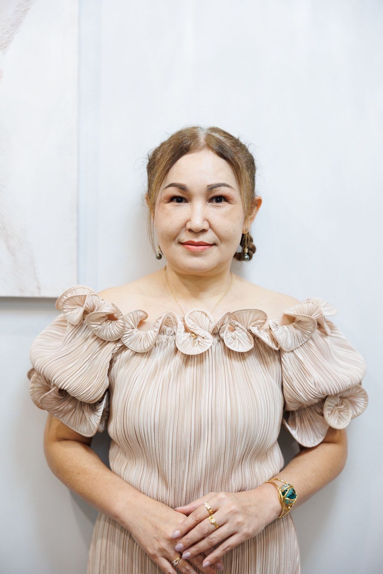 accountant in an off-shoulder beige dress standing against a light background in Phuket.