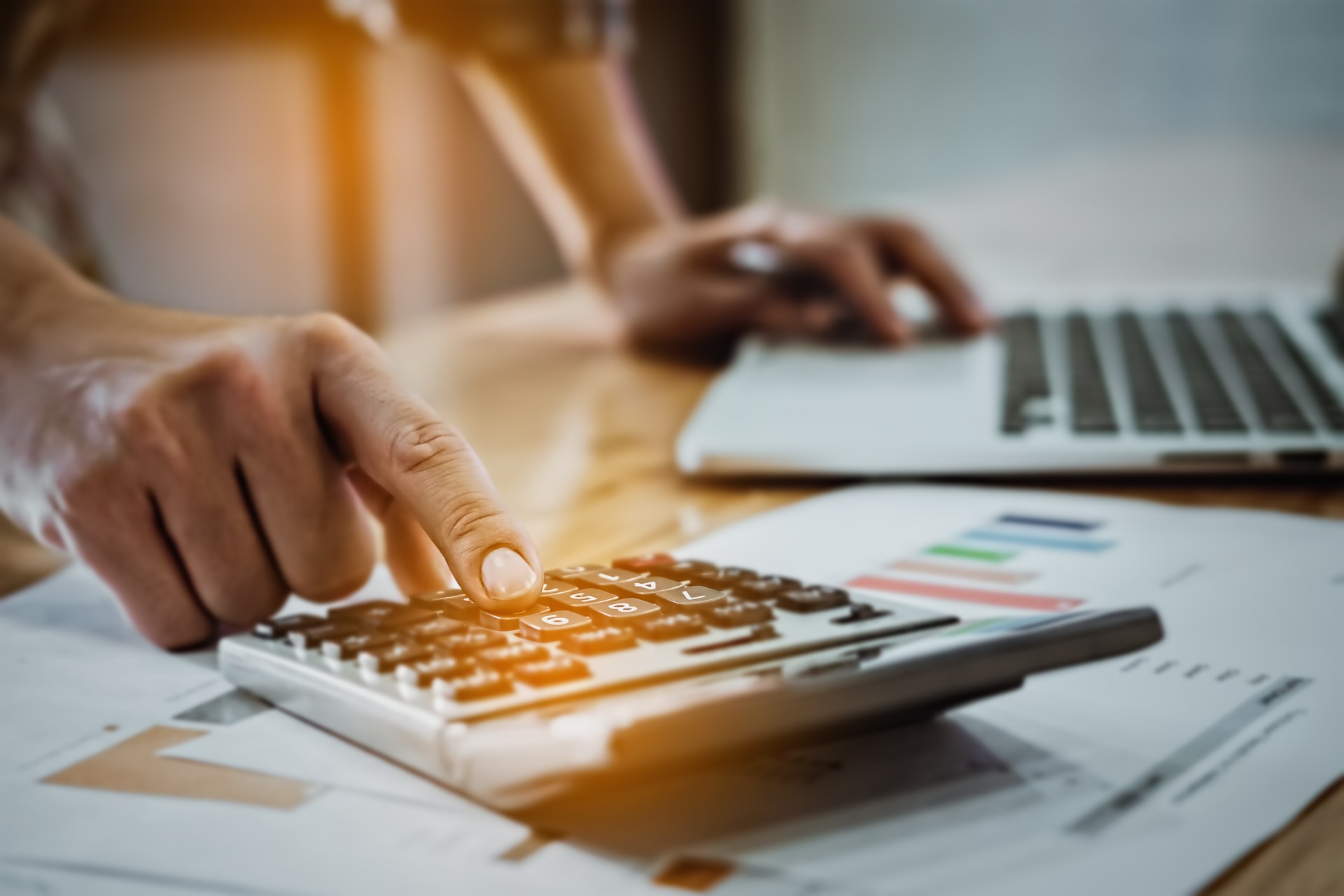 Young business man using calculator and laptop with graph chart