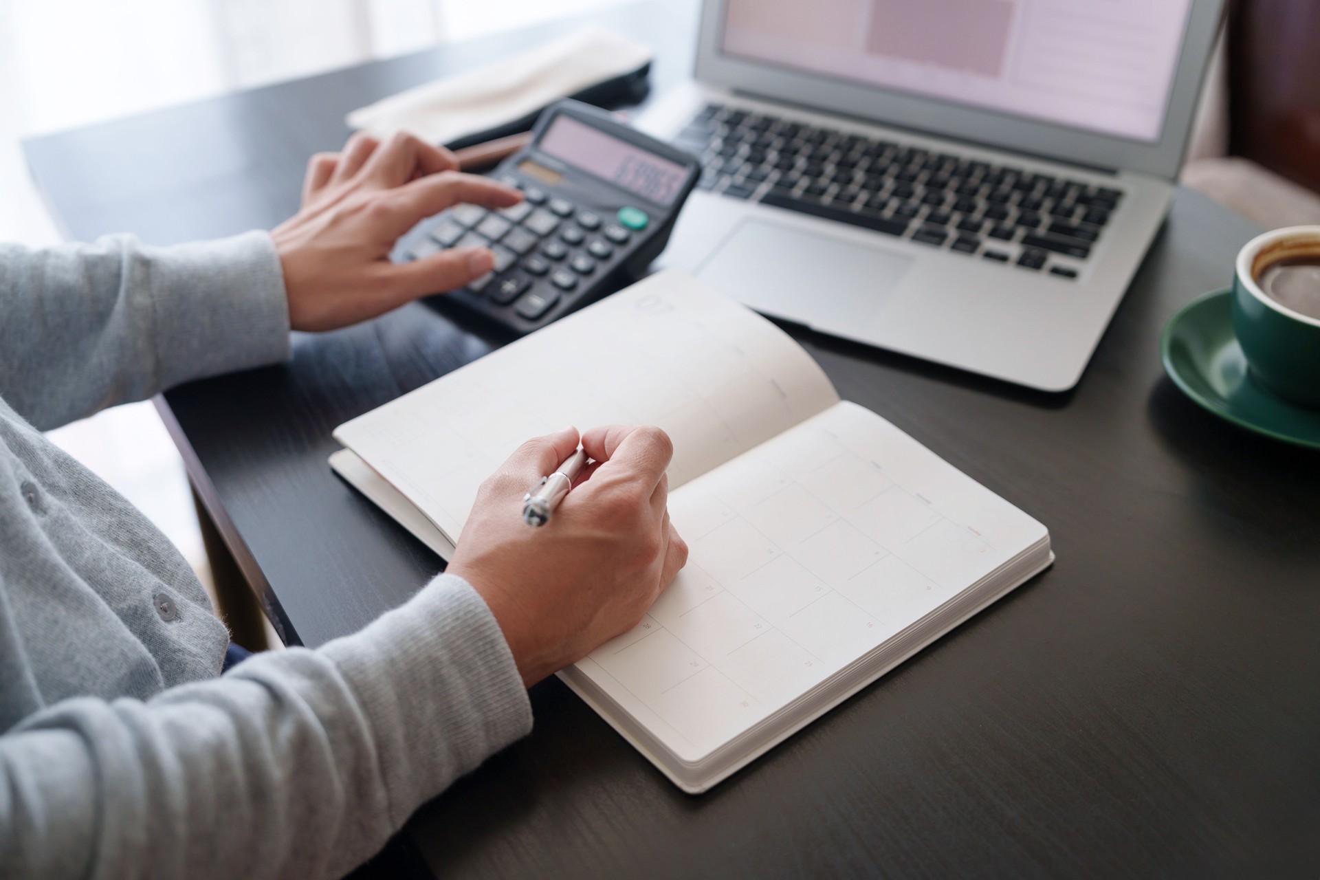 Cropped shot of Asian woman sitting at table doing financial plan and budget with calculator and laptop